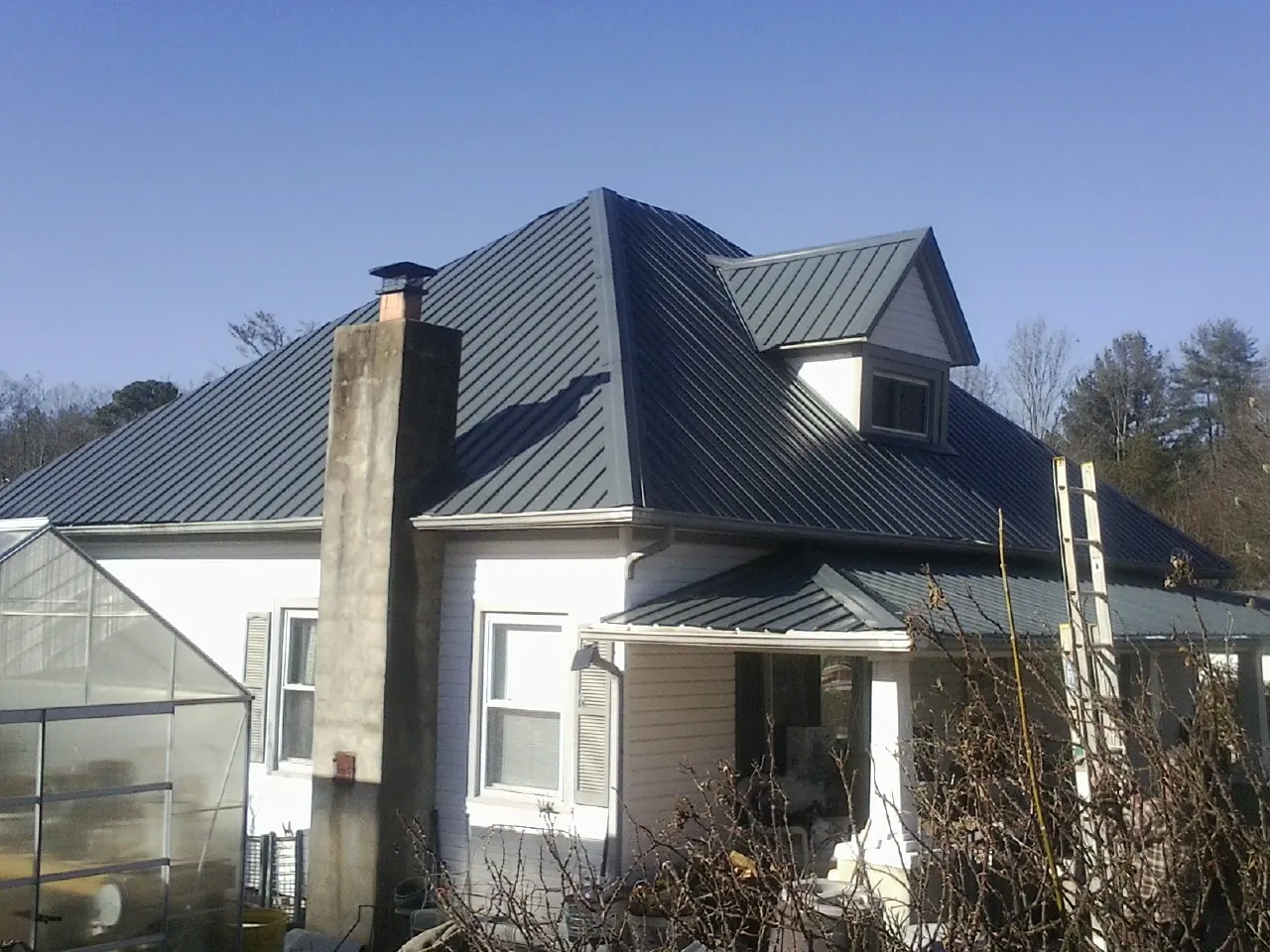 Dark blue standing seam metal roof on a white farmhouse with dormer — Slate & Tile Roof Repair by Roofing Brothers in Wolfeboro