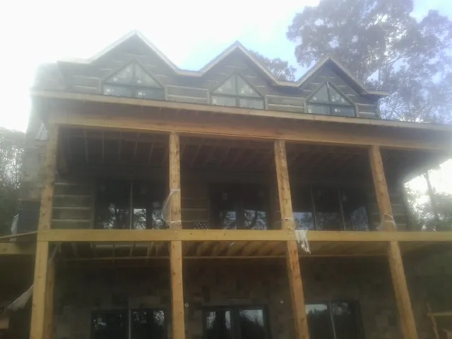 Dormers and porch framing on a large log home under construction — Roof Coating work by our crew in Wolfeboro