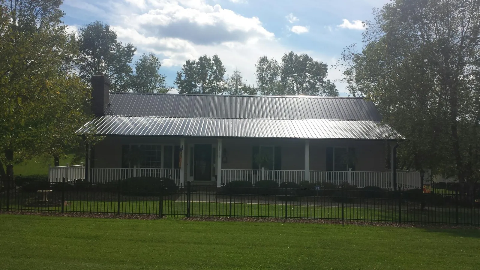 Gray metal roof on a brick ranch with a full width front porch — Gutter Guard Installation work by our crew in Wolfeboro