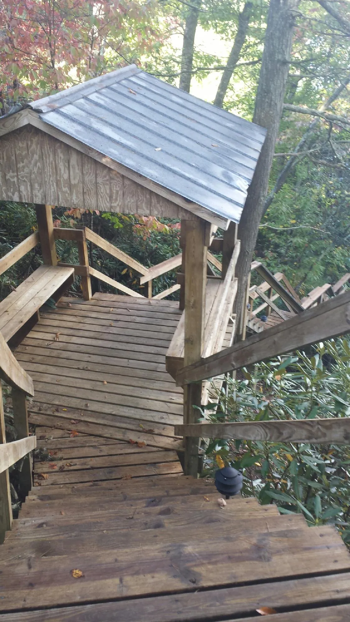 Metal roofed shelter over wooden steps on a wooded walkway — Skylight Repair & Installation work by our crew in Wolfeboro