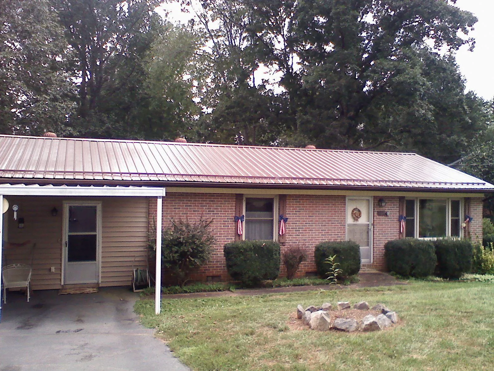 Bronze metal roof and carport on a brick ranch home — Roof Repair work by our crew in Wolfeboro